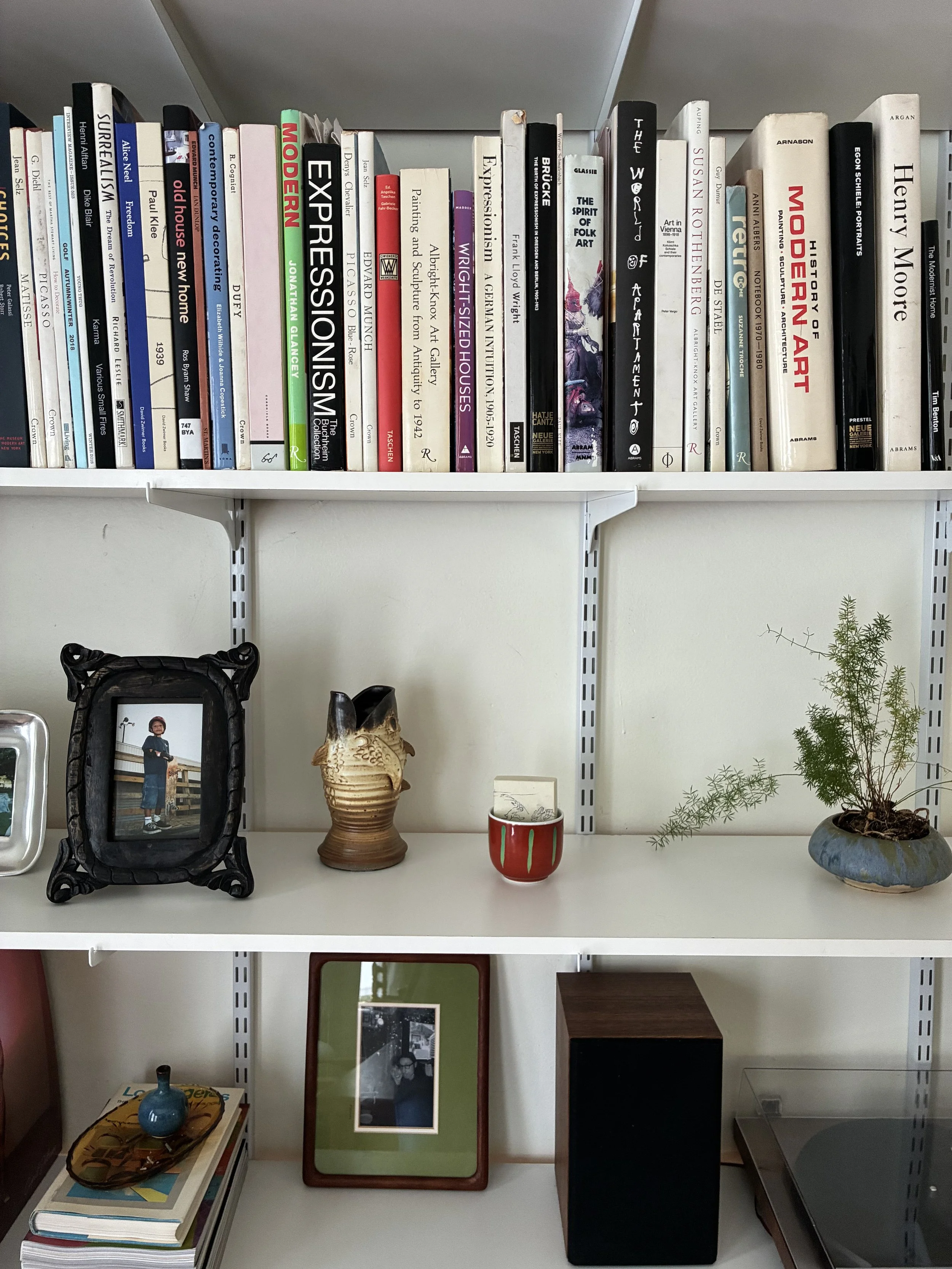 Bookshelves with books, framed photographs, plants, and decorative objects.