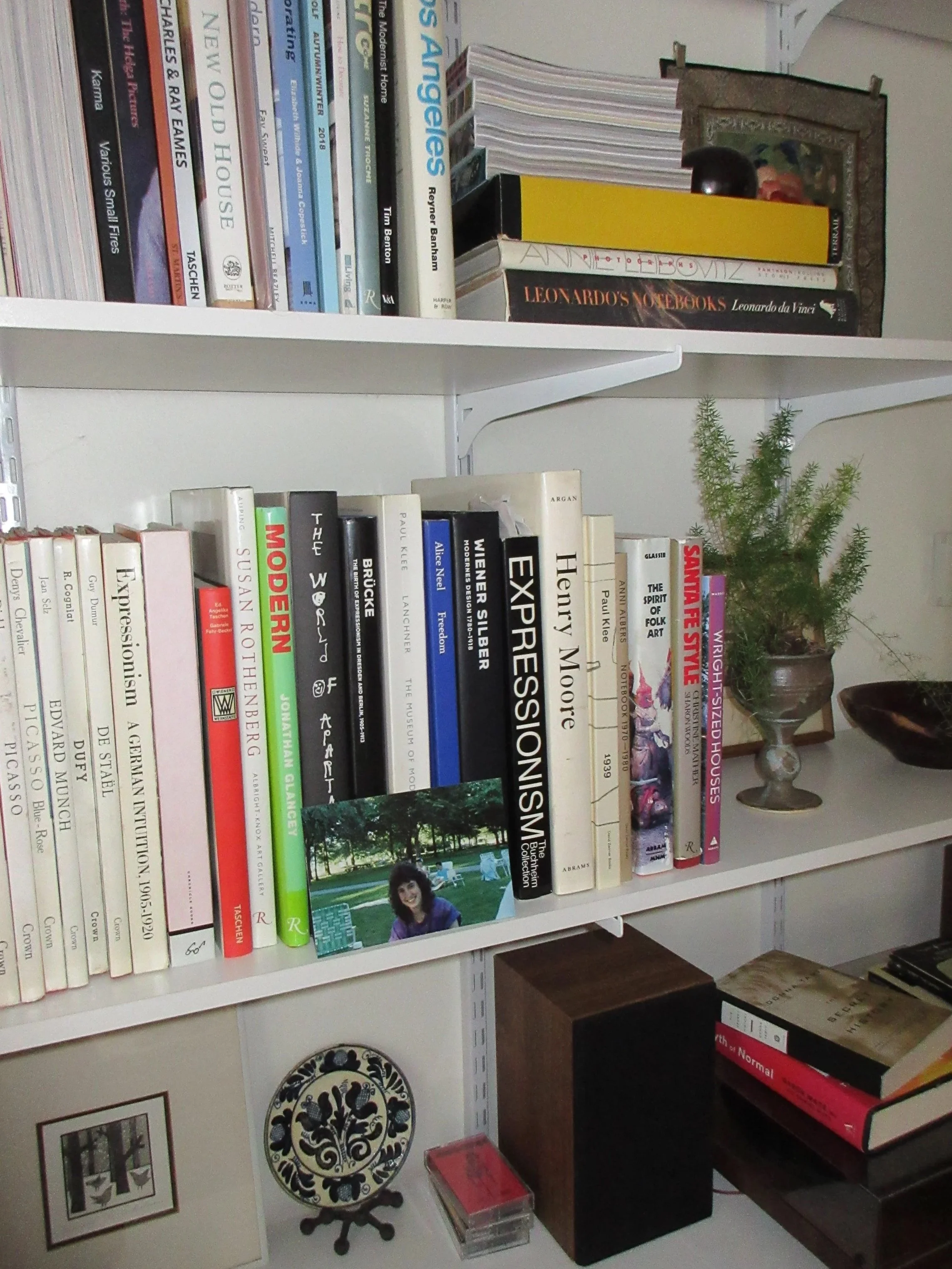 Bookshelves filled with books, a potted plant, framed artwork, and decorative items.