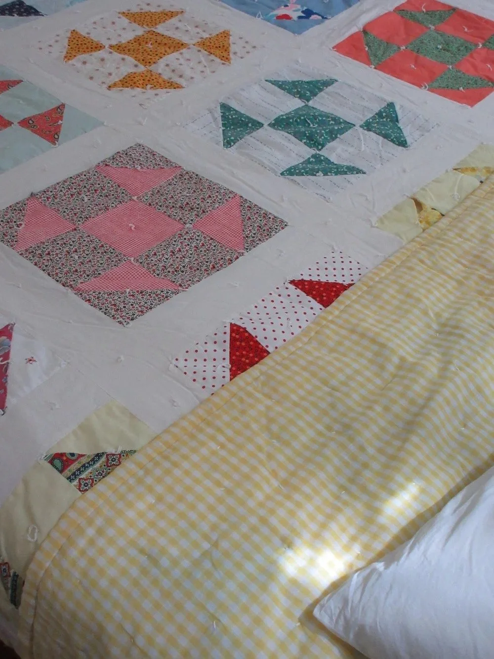 Close-up of a patchwork quilt with various colorful patterns, decorated with a yellow gingham border.
