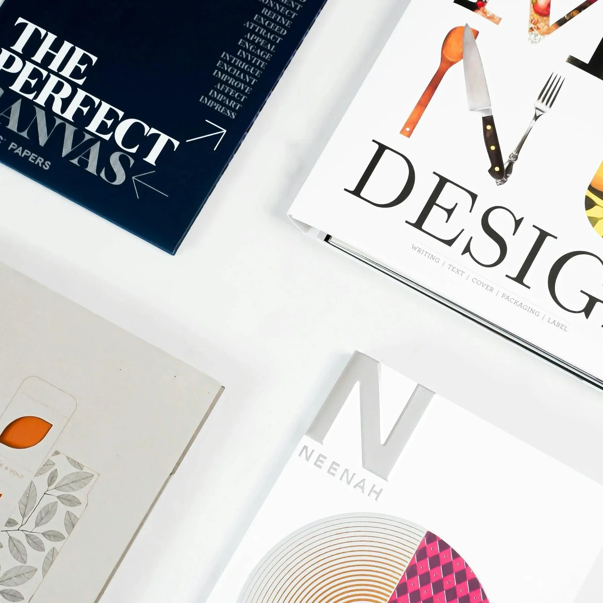 Top view of three design books on a white surface. The books are titled 'The Perfect Package,' 'Design,' and 'Neenah,' featuring various design-related covers and typography.