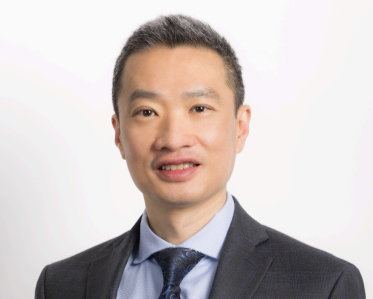 Professional headshot of a man wearing a suit and tie, smiling against a plain white background.