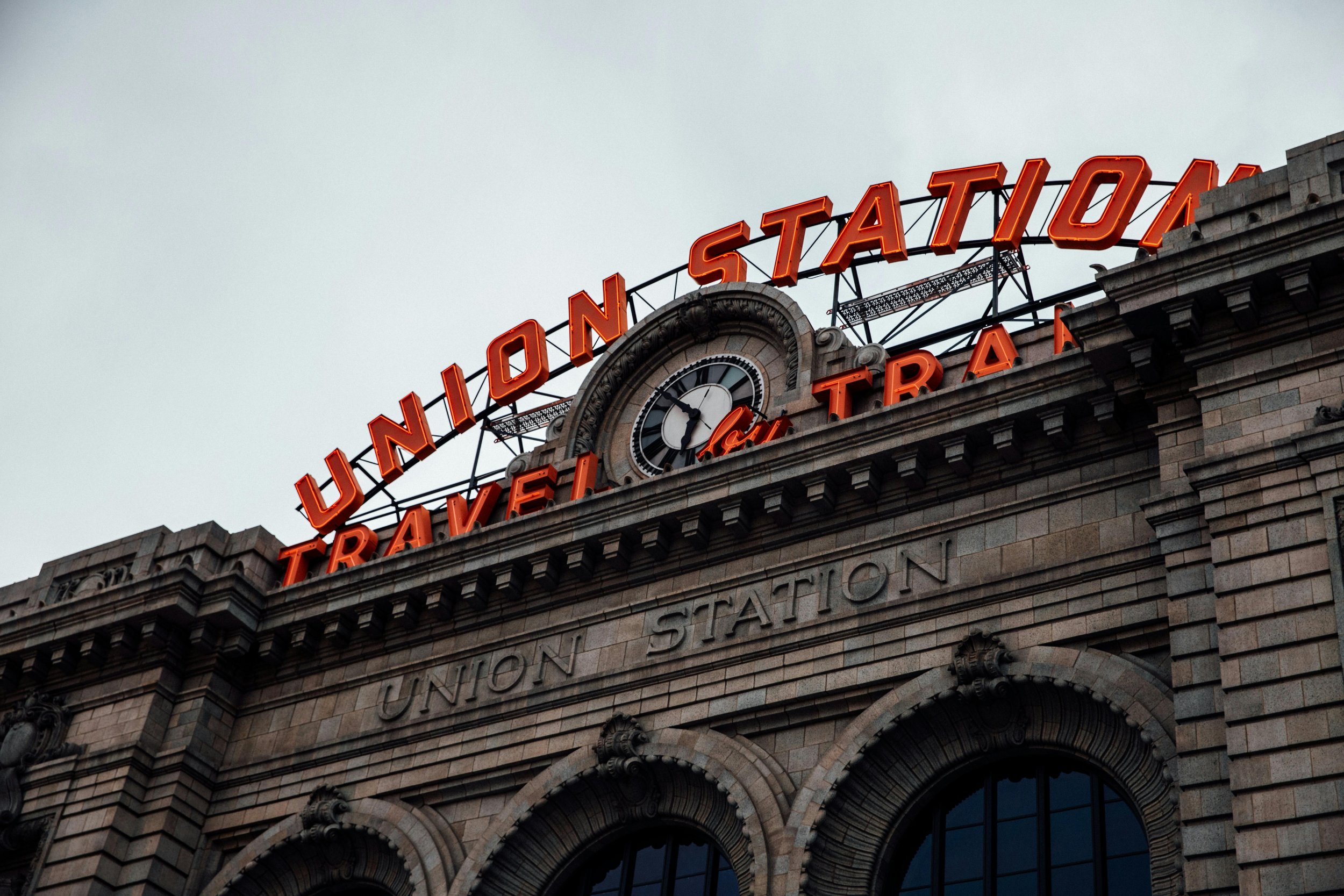 Close-up of a historic train station building with a illuminated red sign reading 'Union Station' with a clock and decorative architectural details.