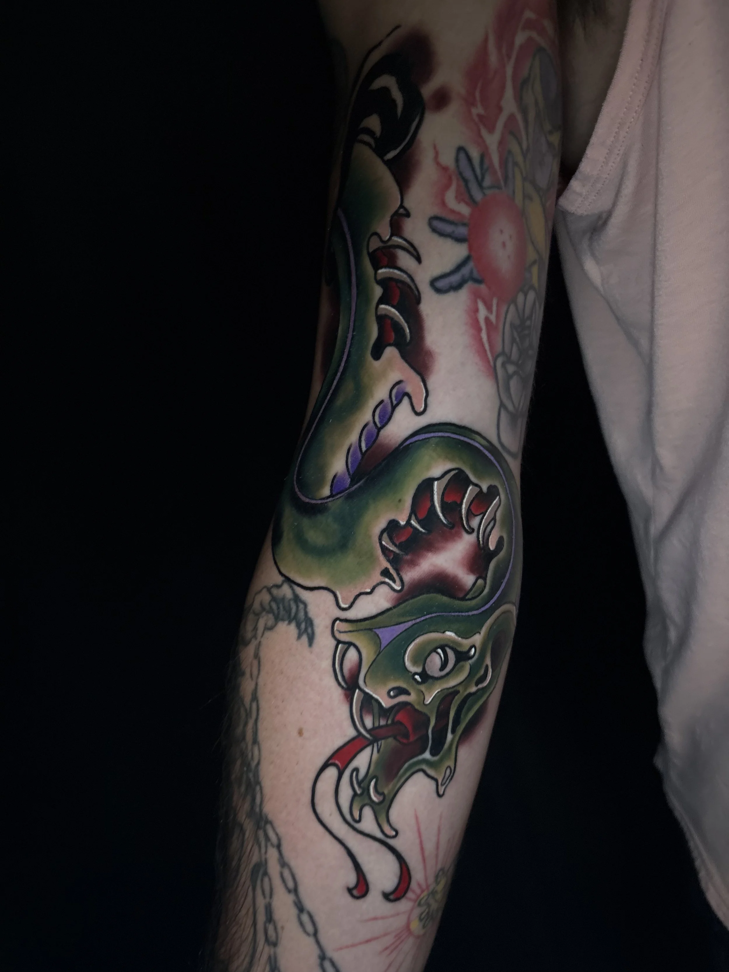 A person's arm with a colorful tattoo featuring a zombie snake.