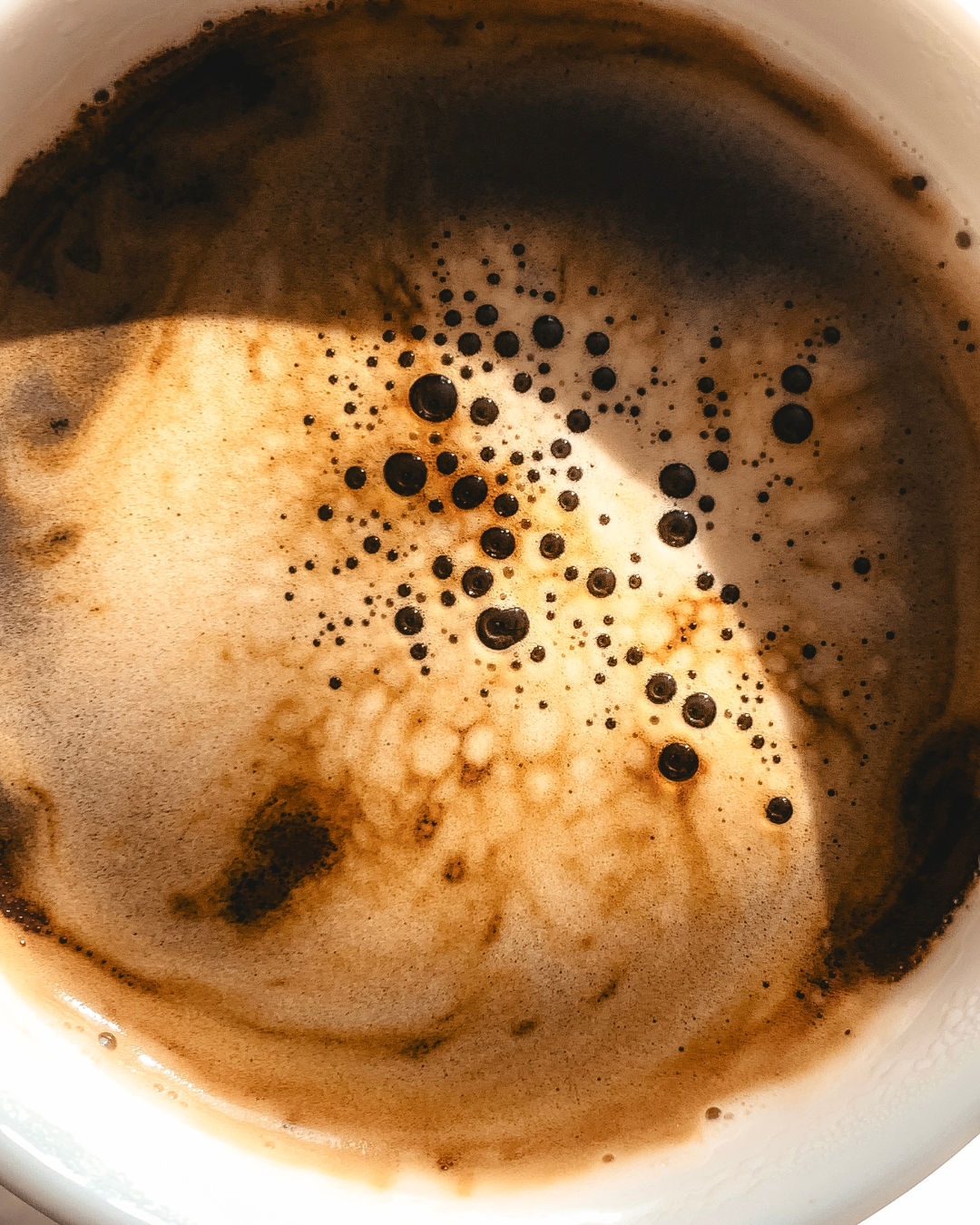 Close-up of a cup of coffee with foam and bubbles on the surface.