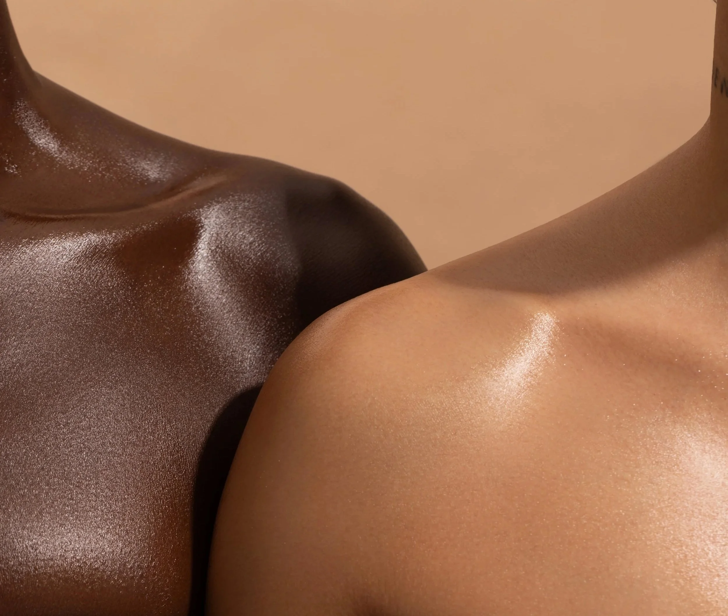 Close-up of two intertwined human bodies, revealing their shoulders, necks, and upper backs, with shimmery skin tones and smooth textures, against a plain beige background.