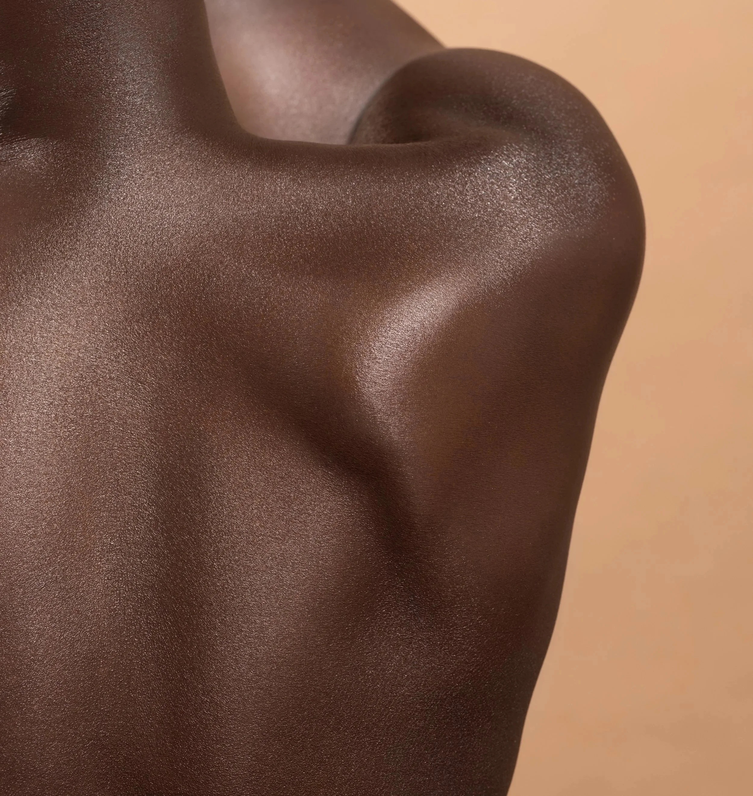Close-up of a person’s shoulder and neck with smooth, dark skin, captured from an angle.