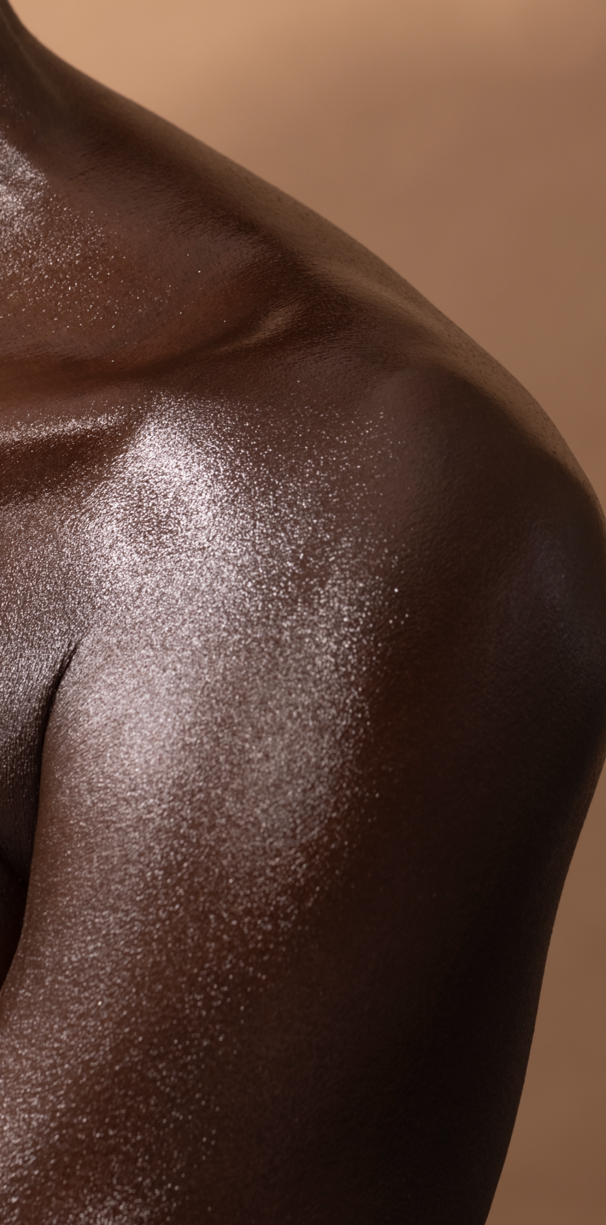 Close-up of a person's shoulder and upper back with shiny, dark skin.