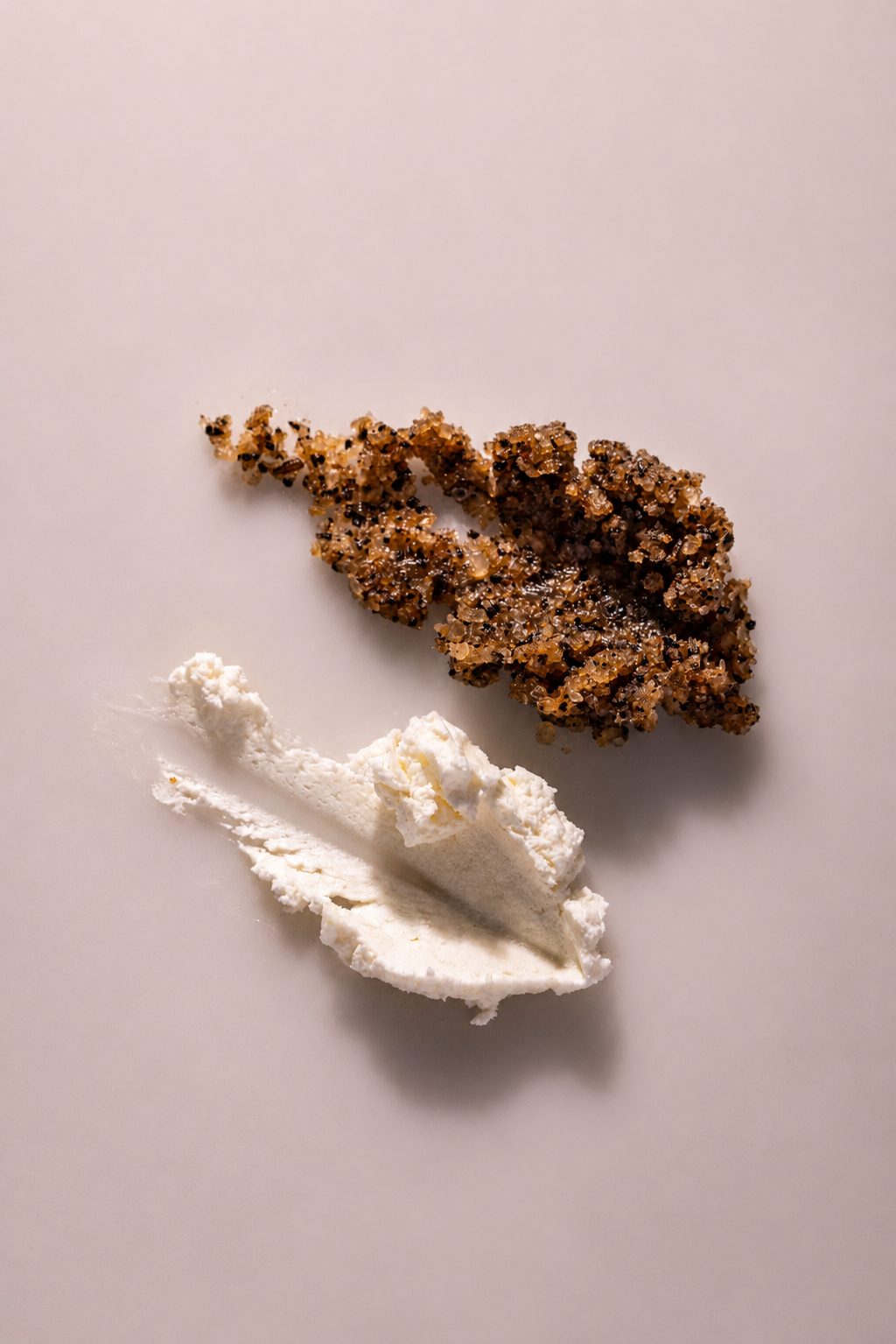 A scoop of vanilla ice cream with a almond brittle candy on a white surface.