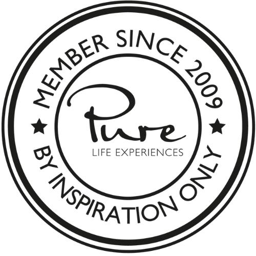 A circular black logo with white text that reads "Member Since 2009" and "By Inspiration Only." The center features the words "Pure Life Experiences" and a stylized script of the word "Pure."