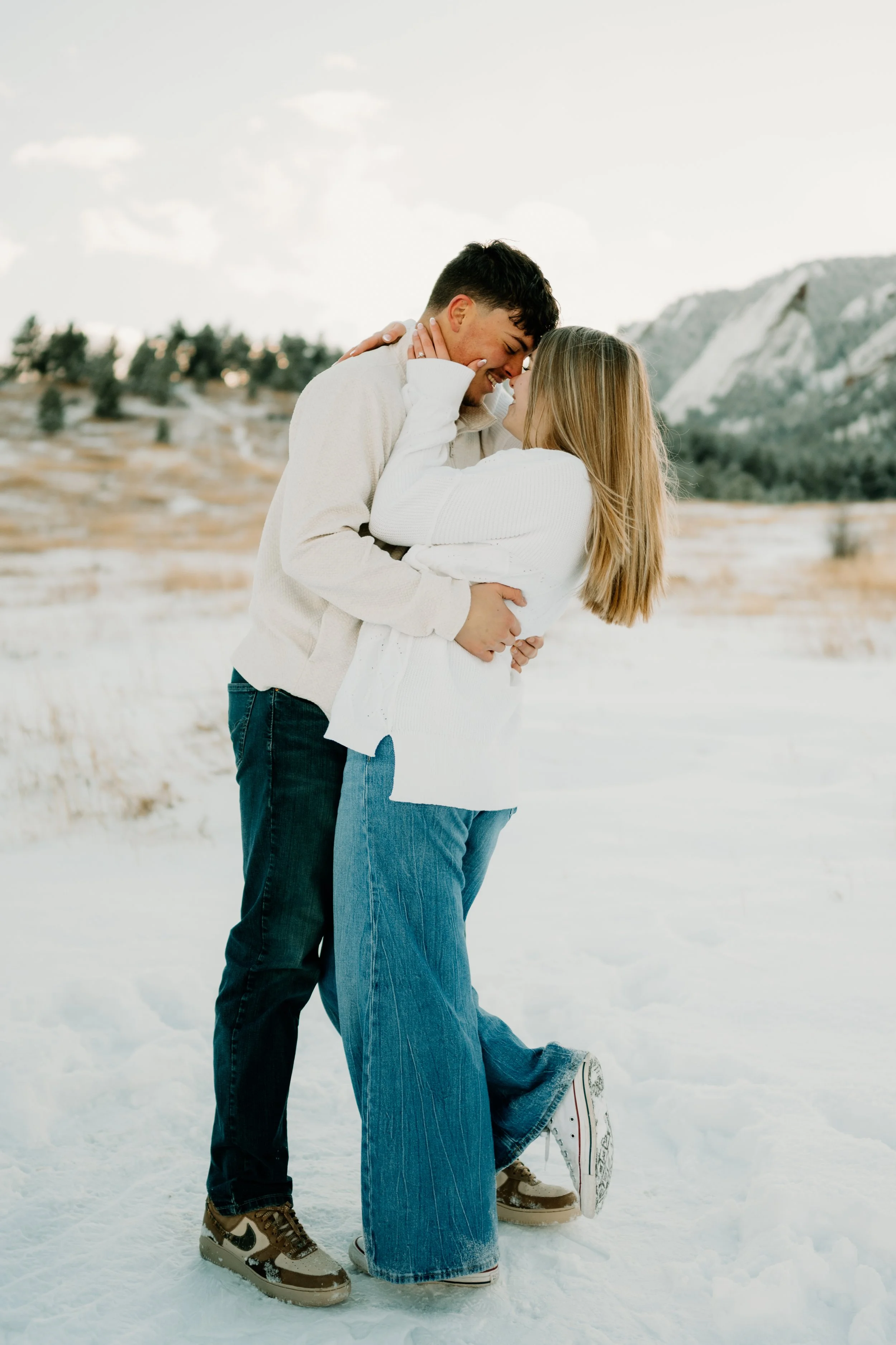 An engaged couple hugging each other during golden hour in the snowy Colorado mountains at Chautauqua Park in Boulder Colorado.