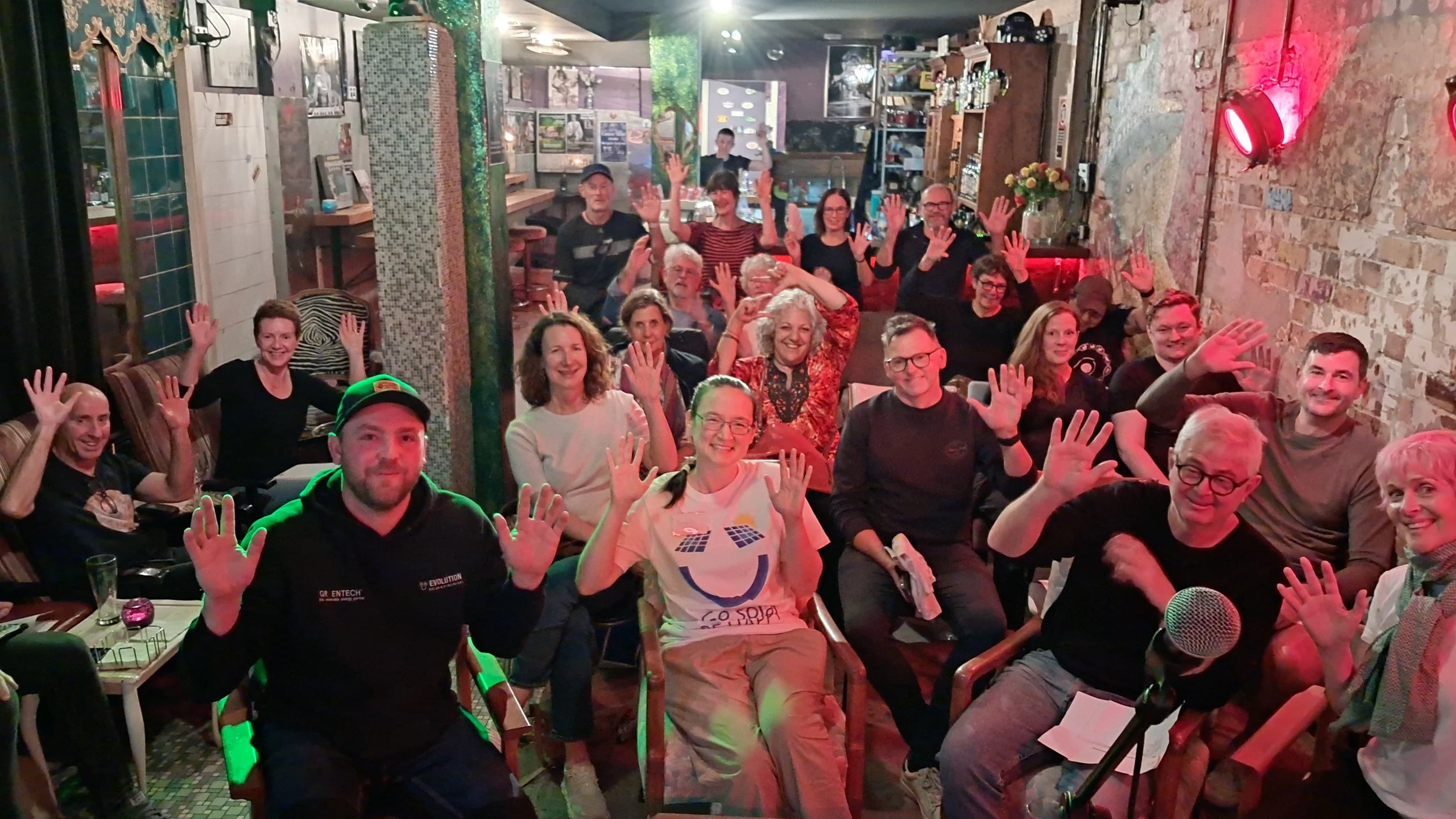A smiling audience waves at the camera.