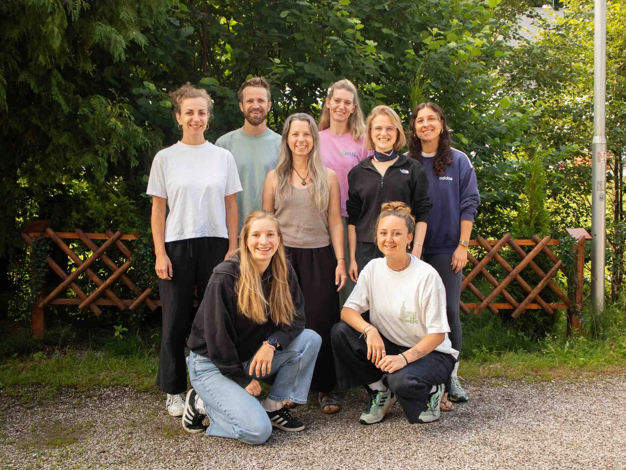 Gruppenfoto des PAN DACH Teams vor einem Zaun und grünen Büschen.
