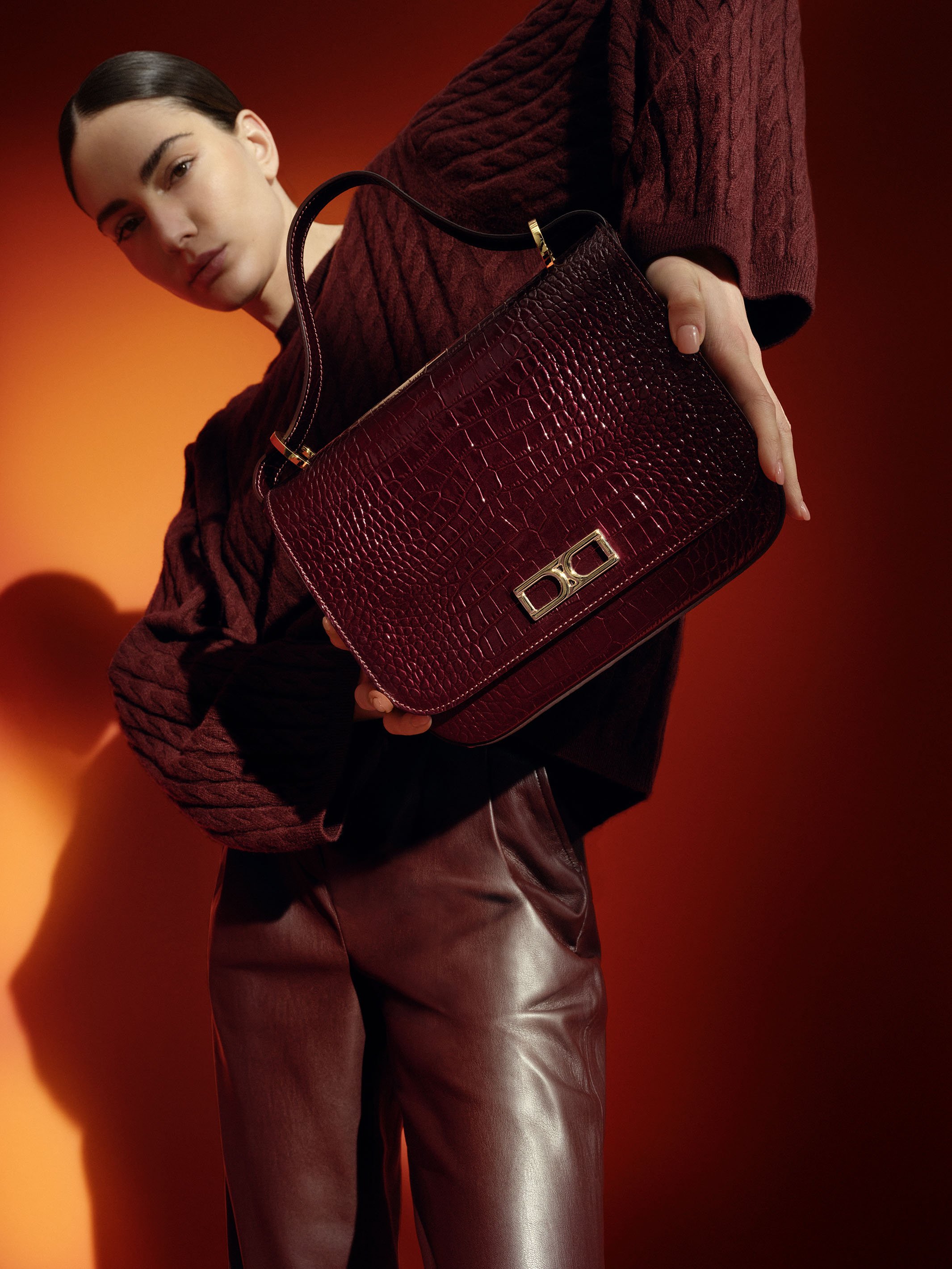 Model im burgundfarbenen Monochrome-Look mit Högl Tasche „Meg“ in Cabernet-Krokolack, Studioaufnahme F/W 2023 von imagespy.