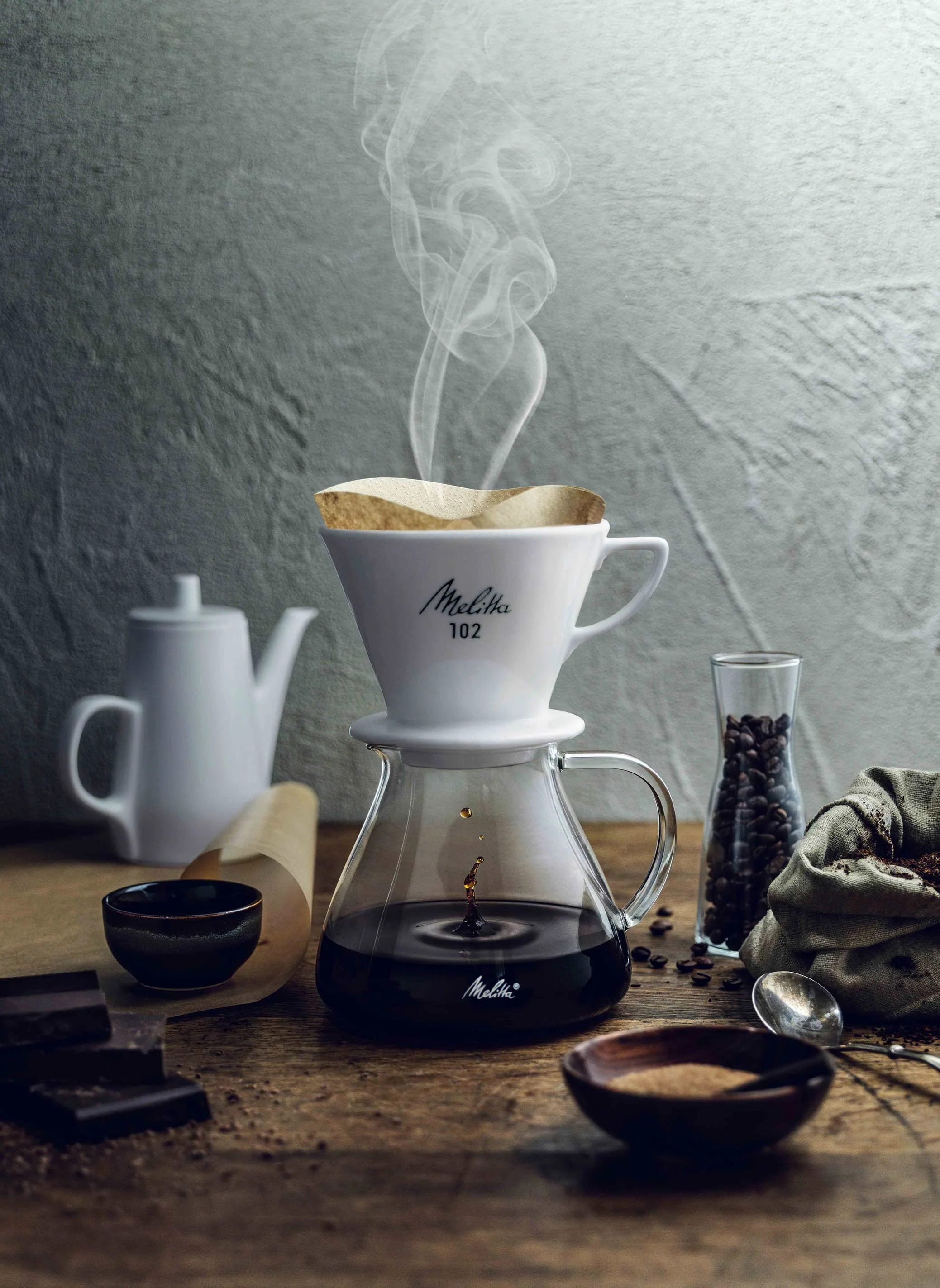 Klassischer Melitta Porzellan-Handfilter 102 beim Pour-Over-Brühvorgang mit aufsteigendem Dampf, inszeniert von imagespy zum 111-jährigen Markenjubiläum.