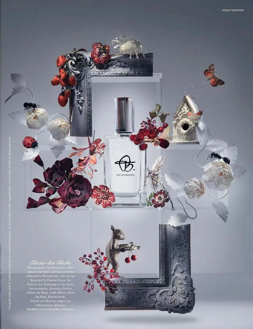 Stillleben-Umsetzung von imagespy für das VOGUE Editorial „Elixier des Glücks“: Ein Flakon in barocken Rahmenfragmenten, dekoriert mit roten Blüten, Beeren und kleinen Tierfiguren.