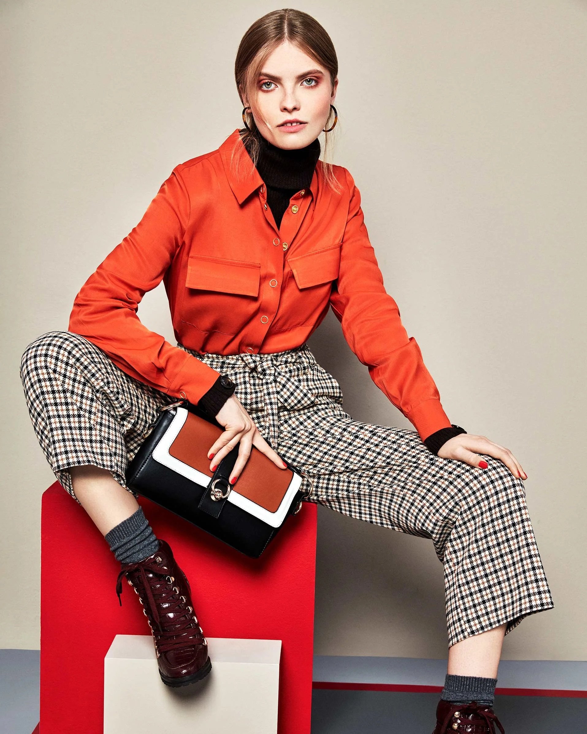PR-Lookbook Cover von C&A Fall/Winter 2019, Model sitzt auf Podest mit orangefarbenem Hemd und karierter Hose, Editorial-Stil, fotografiert von imagespy.