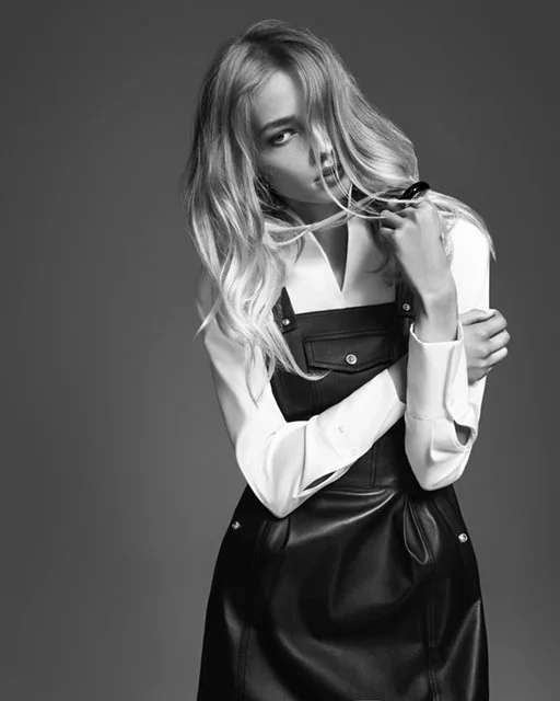 Schwarzweiß-Studioaufnahme 2016 für McArthurGlen/GLAMOUR: Model in weißem Shirt mit Leder-Latzrock, modischer Stilbruch mit präzisen Schnitten und neuen Kragenformen, umgesetzt von imagespy.