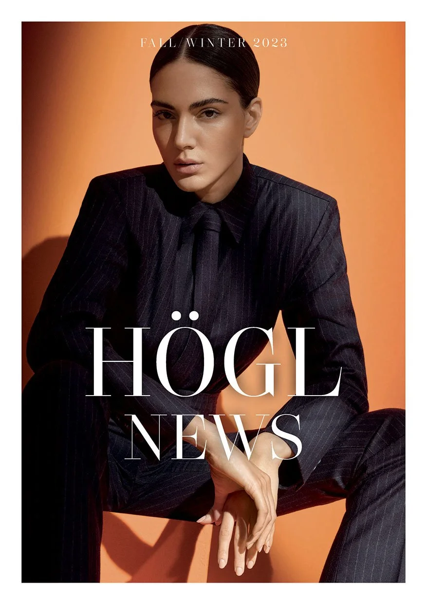 Cover der Högl Newspaper F/W 2023 mit Model im schwarzen Nadelstreifenanzug vor orangem Hintergrund, inszeniert von imagespy.