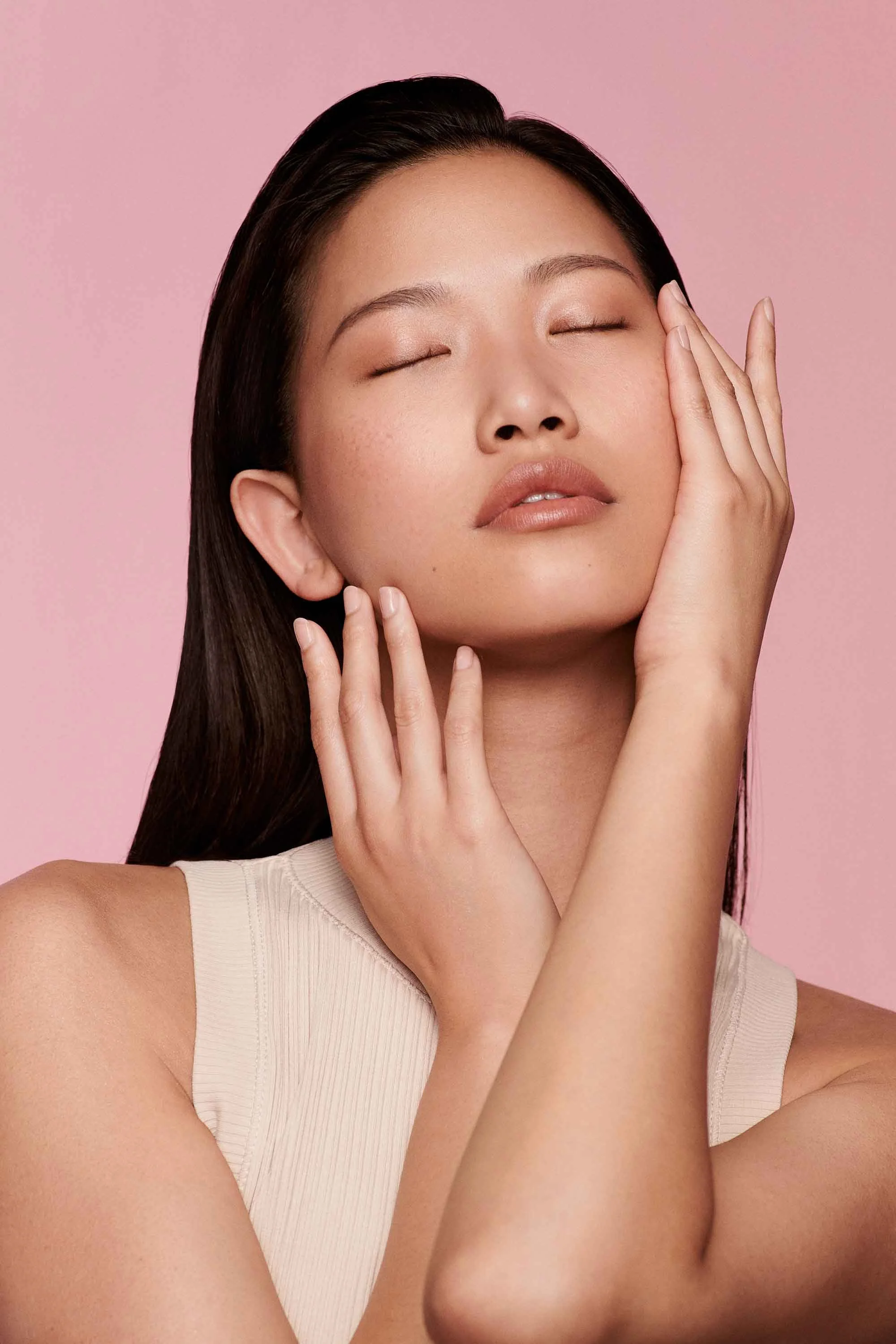 Zoeva Markenrelaunch umgesetzt von imagespy, Porträt einer Frau mit geschlossenen Augen und sanfter Berührung vor rosa Hintergrund, Fokus auf Hautgefühl und visuelle Markenidentität.