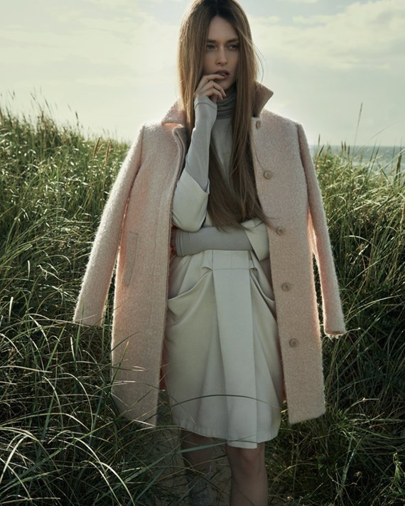 Farbiges Fashion-Bild für Hessnatur x ELLE: Model in rosa Wollmantel steht verträumt in hoher Wiese, Bezug zur Natur, umgesetzt von imagespy.