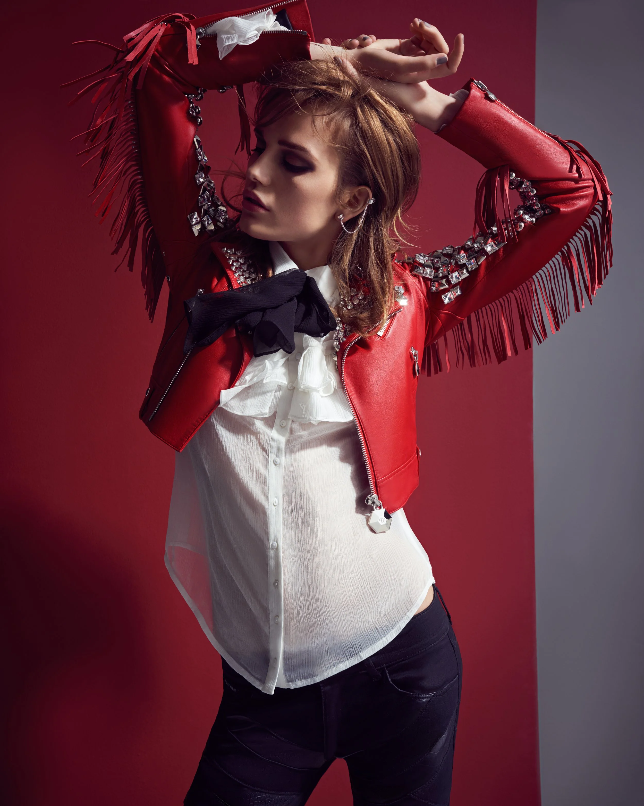 Model posiert für McArthurGlen/GLAMOUR in roter Lederjacke und -hose von Philipp Plein, Rüschenbluse von Anne Fontaine, Ohrringe von Atelier Swarovski by Jean Paul Gaultier – glamouröse High-End-Fashion-Fotografie von imagespy.