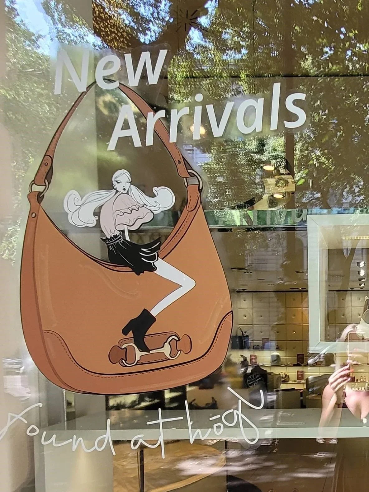 Nahaufnahme eines Högl Schaufensterstickers: Illustration einer Frau auf Tasche, begleitet von Text ‚New Arrivals found at Högl‘.