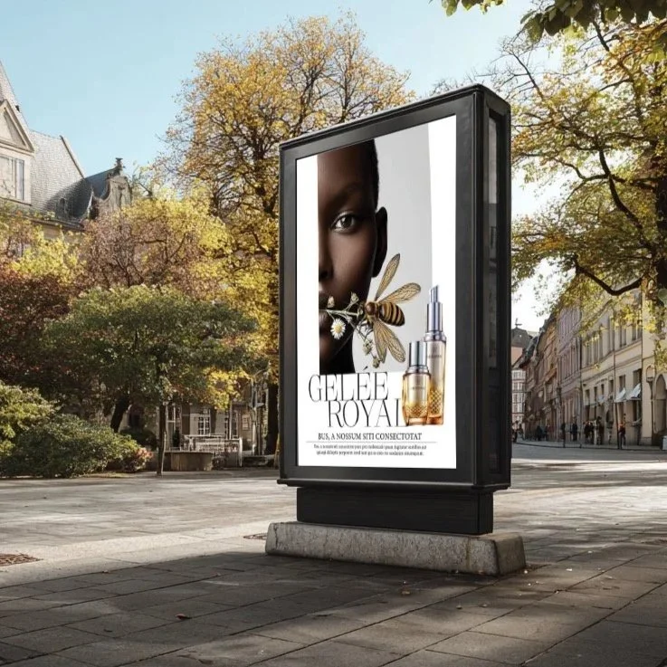 Ein digitales Werbedisplay zeigt die Gelée Royal Kampagne von imagespy: KI-generiertes Portrait und Produktdesign mit goldenen Flakons, erstellt mit dem Tool Nani.