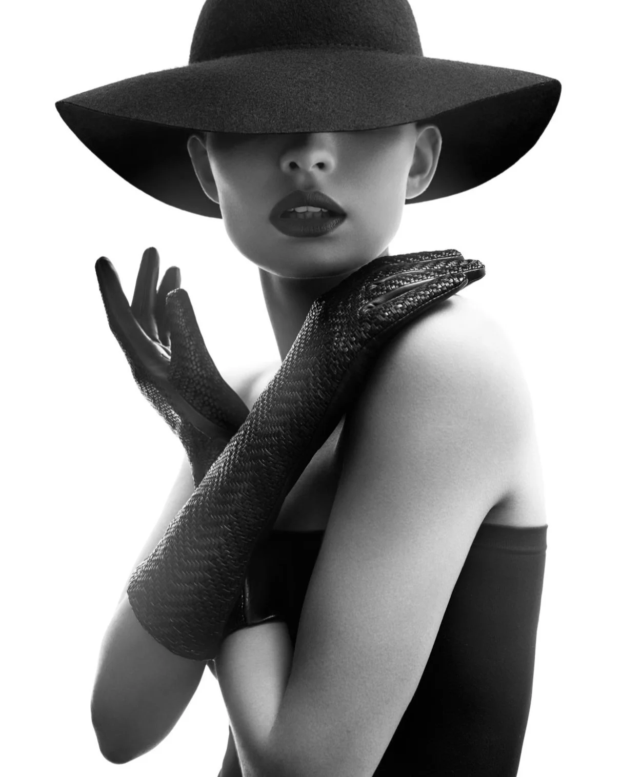 Minimalistische Schwarzweiß-Aufnahme einer Frau im schwarzen Kleid mit Hut und Lederhandschuhen aus der Roeckl Fall/Winter 2017 Kollektion, umgesetzt von imagespy.