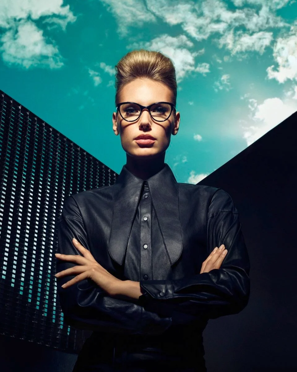 Frau in schwarzem Shirt mit Rodenstock Brille vor blau-wolkigem Himmel, Visual 2019 umgesetzt von imagespy.