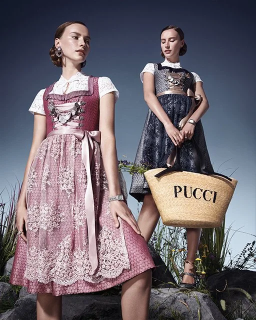 Models in Tracht, blau und rosa, posieren auf großen Steinen vor einer hohen Wiese; eine trägt eine Pucci Strohtasche – moderne Trachteninszenierung von imagespy für Vogue und Lodenfrey.