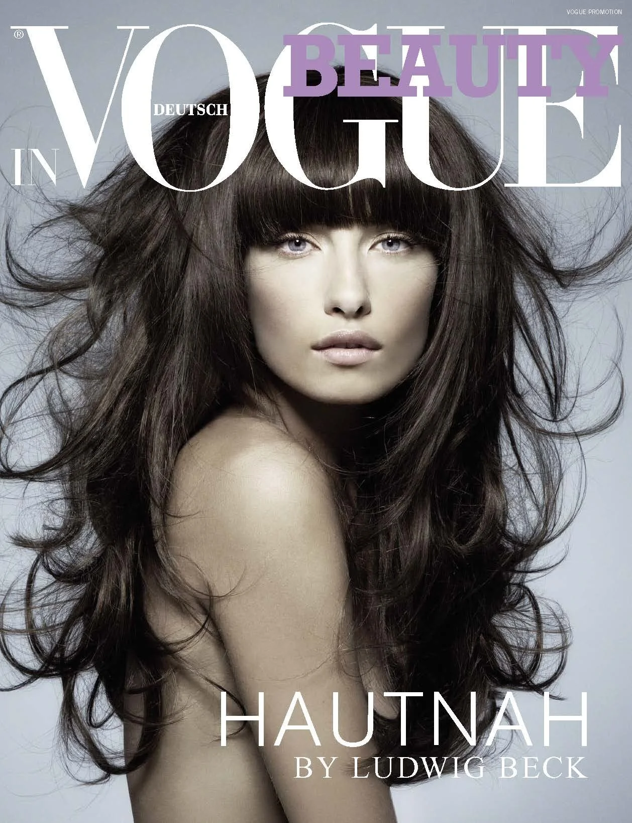 VOGUE Beauty Promotion Cover Hautnah by Ludwig Beck, umgesetzt von imagespy, Porträt einer Frau mit voluminösem braunem Haar und Pony vor hellem Hintergrund.