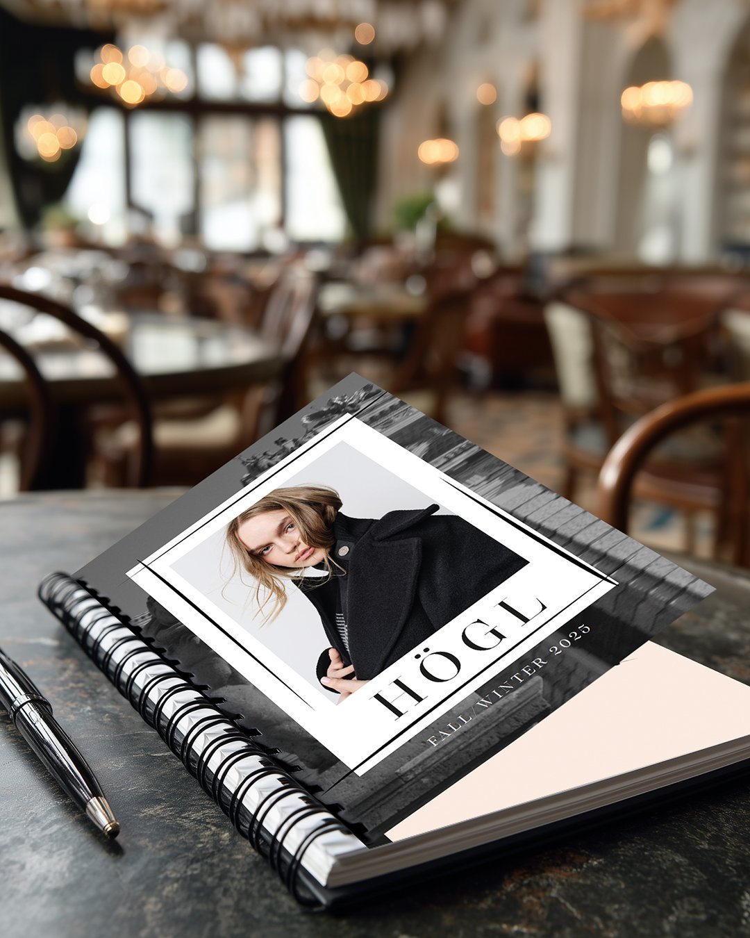 Högl Fall/Winter 2025 Notizbuch liegt auf einem Café-Tisch – kampagnenbegleitendes Lifestyle-Visual, erstellt von imagespy.