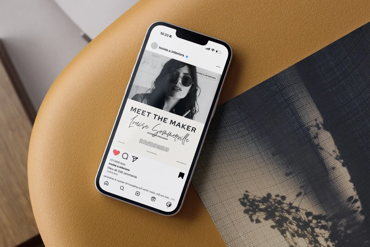 En mobiltelefon som visar ett inlägg om att träffa Louise Gourmecille, en inredningsdesigner, på en gulaktig yta med ett konstverk av ett landskap i bakgrunden.