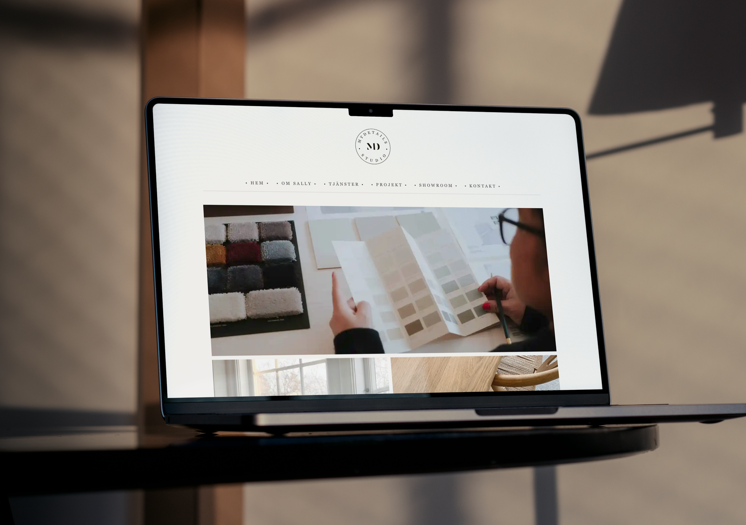 Skärm på en bärbar dator som visar en webbdesign för en inredningsbutik med bilder på färg- och materialprover.
