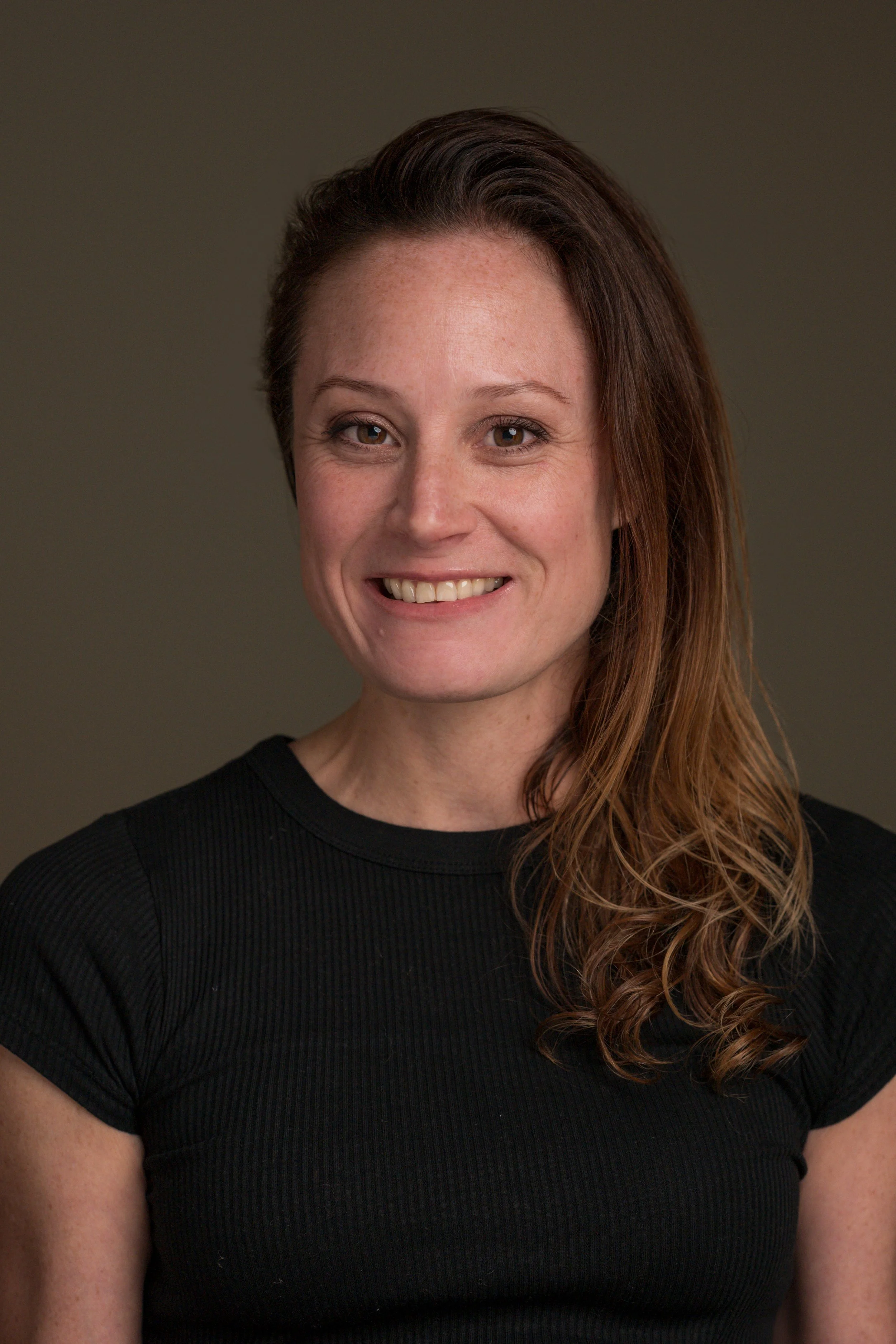 Portrait of a woman with shoulder-length hair wearing a black shirt, against a neutral background.