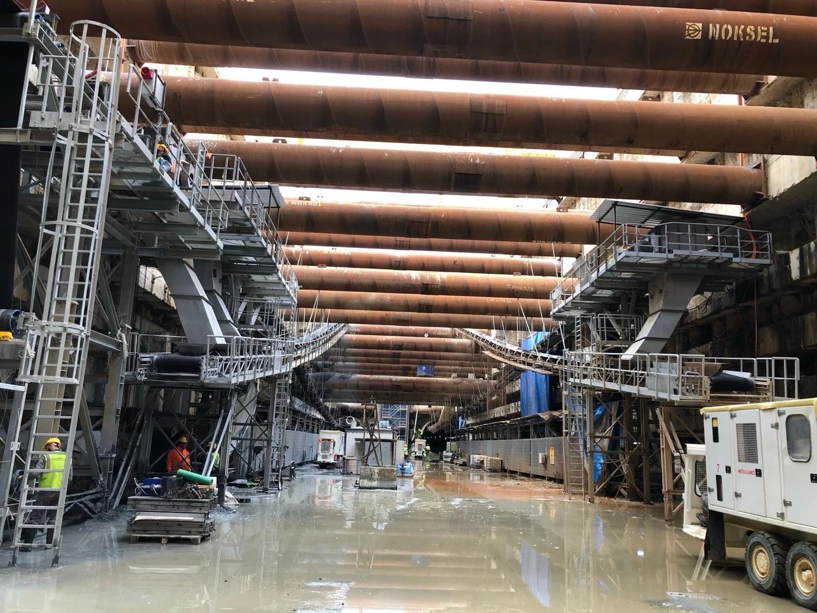 Construction site with large metal pipes and scaffolding