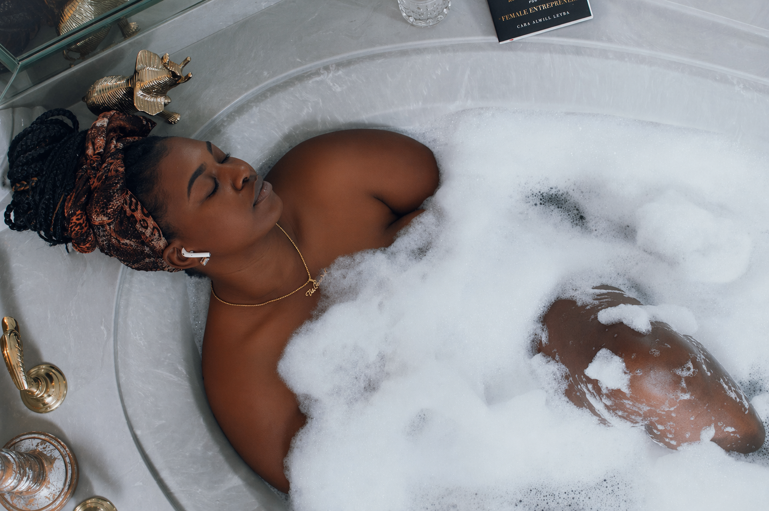 Femme noire prenant un bain rituel relaxant dans une baignoire moussante, symbole de purification émotionnelle, de nouvelle lune et de soin sacré féminin.