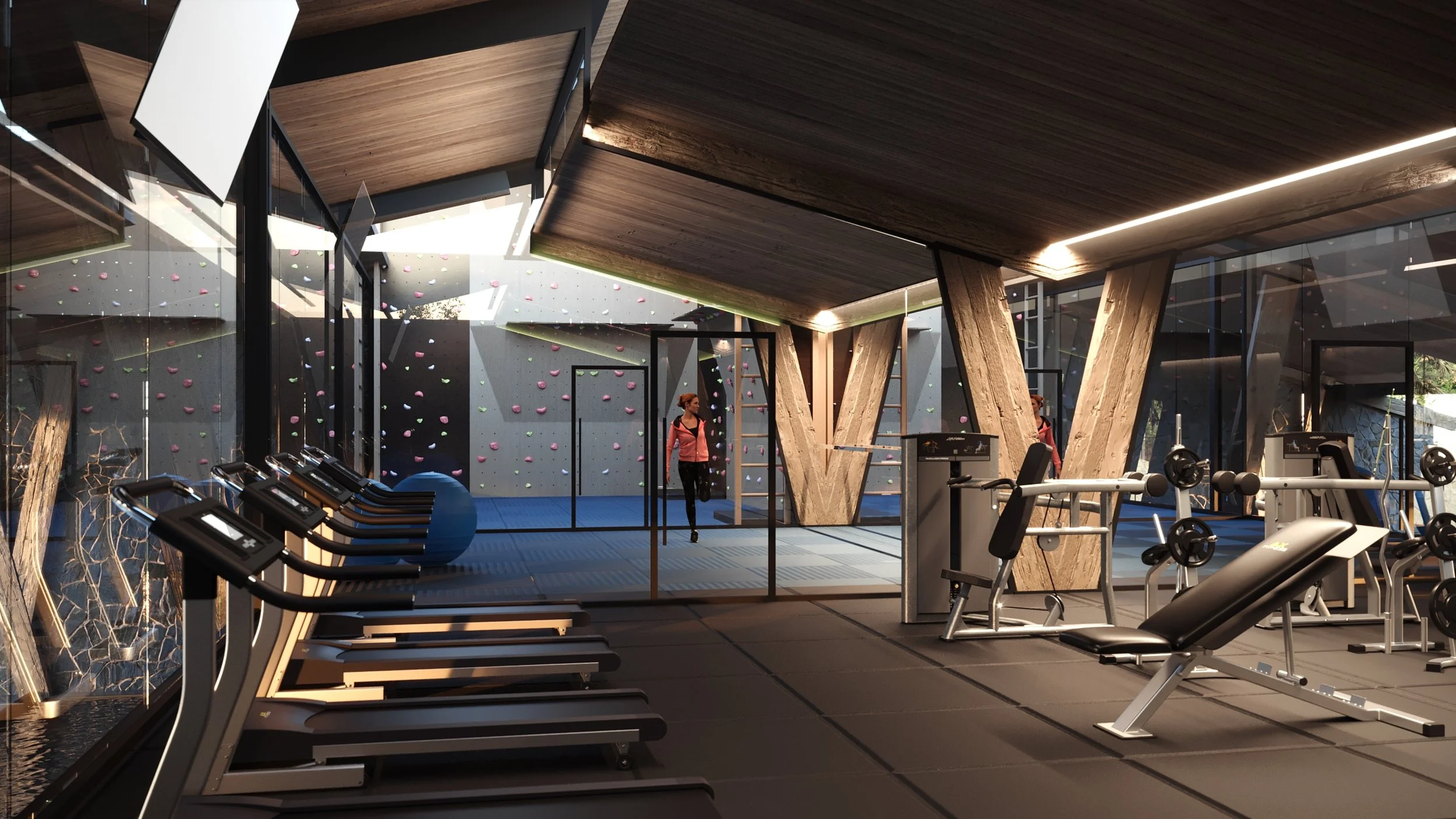 Modern gym with workout equipment, a climbing wall, and a person walking near the climbing area.