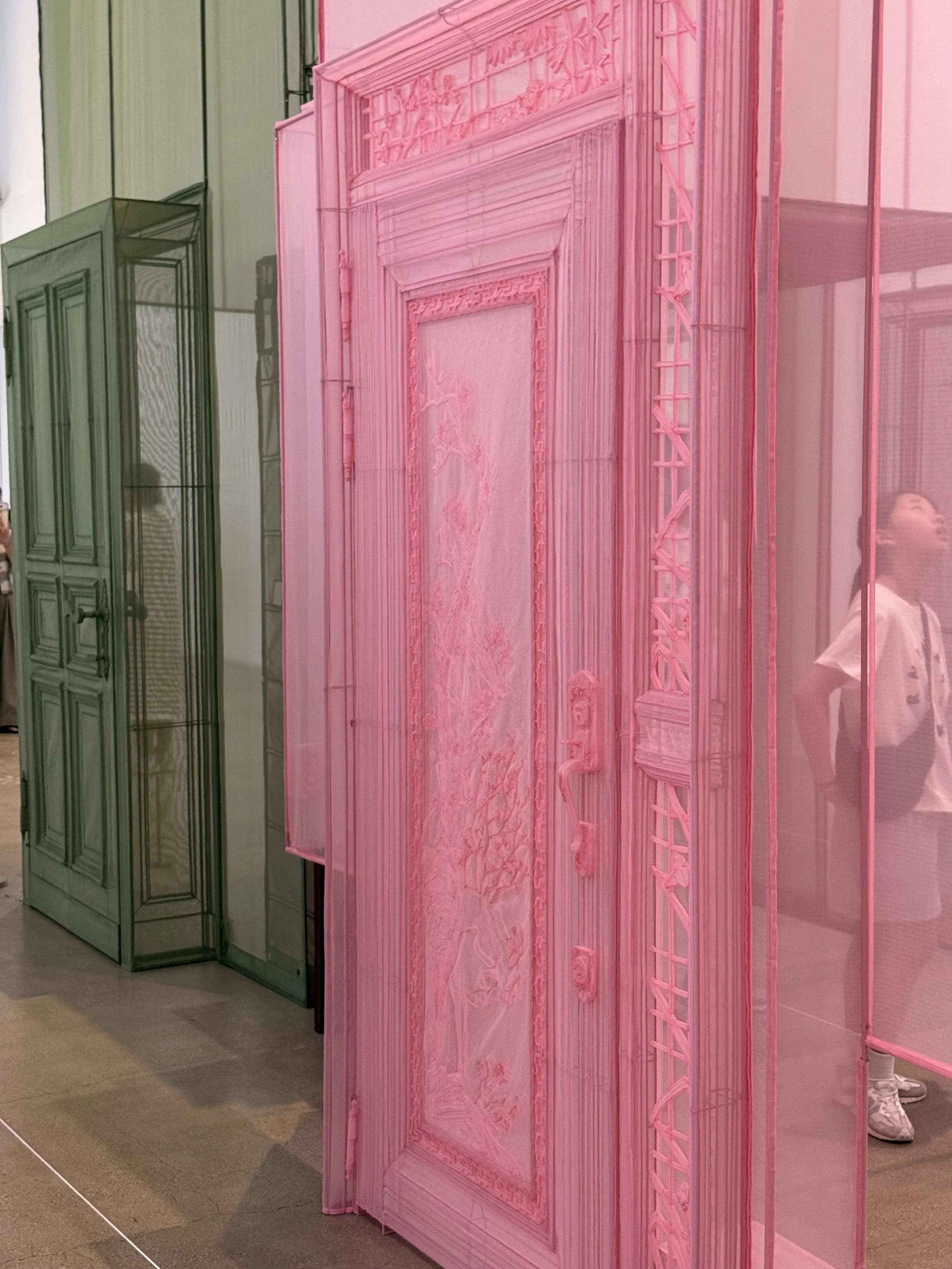 A translucent pink fabric doorway by Do Ho Suh, with a green architectural section visible behind it at MMCA Seoul.