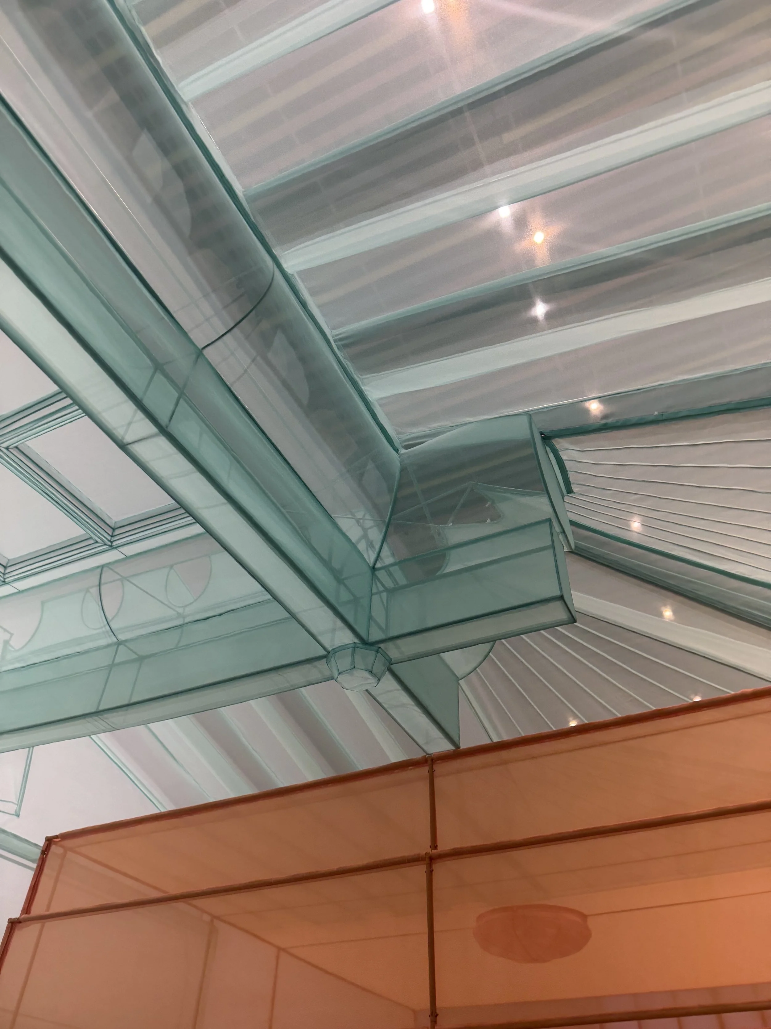 Looking upward through overlapping green and orange translucent fabric structures in Do Ho Suh’s architectural installation at MMCA Seoul.