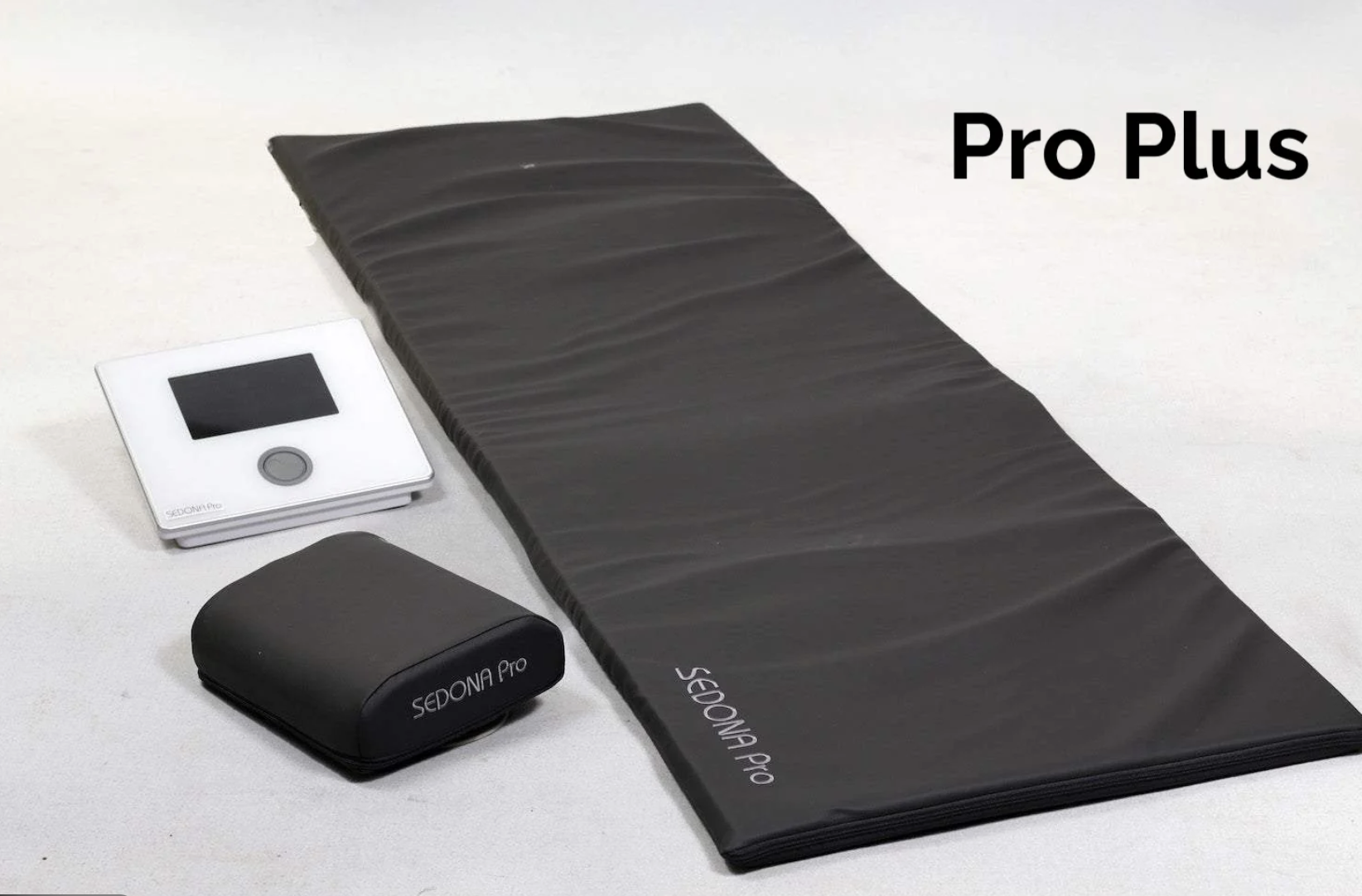 Workout equipment including a black exercise mat, a small white digital scale, and a white and black fitness tracker labeled 'Sedona Pro' on a white surface.
