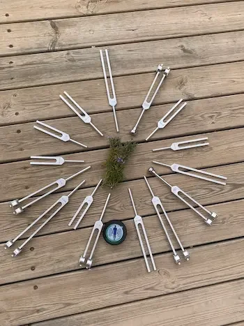 Clock made with garden tools and a small clock in the center on a wooden deck.