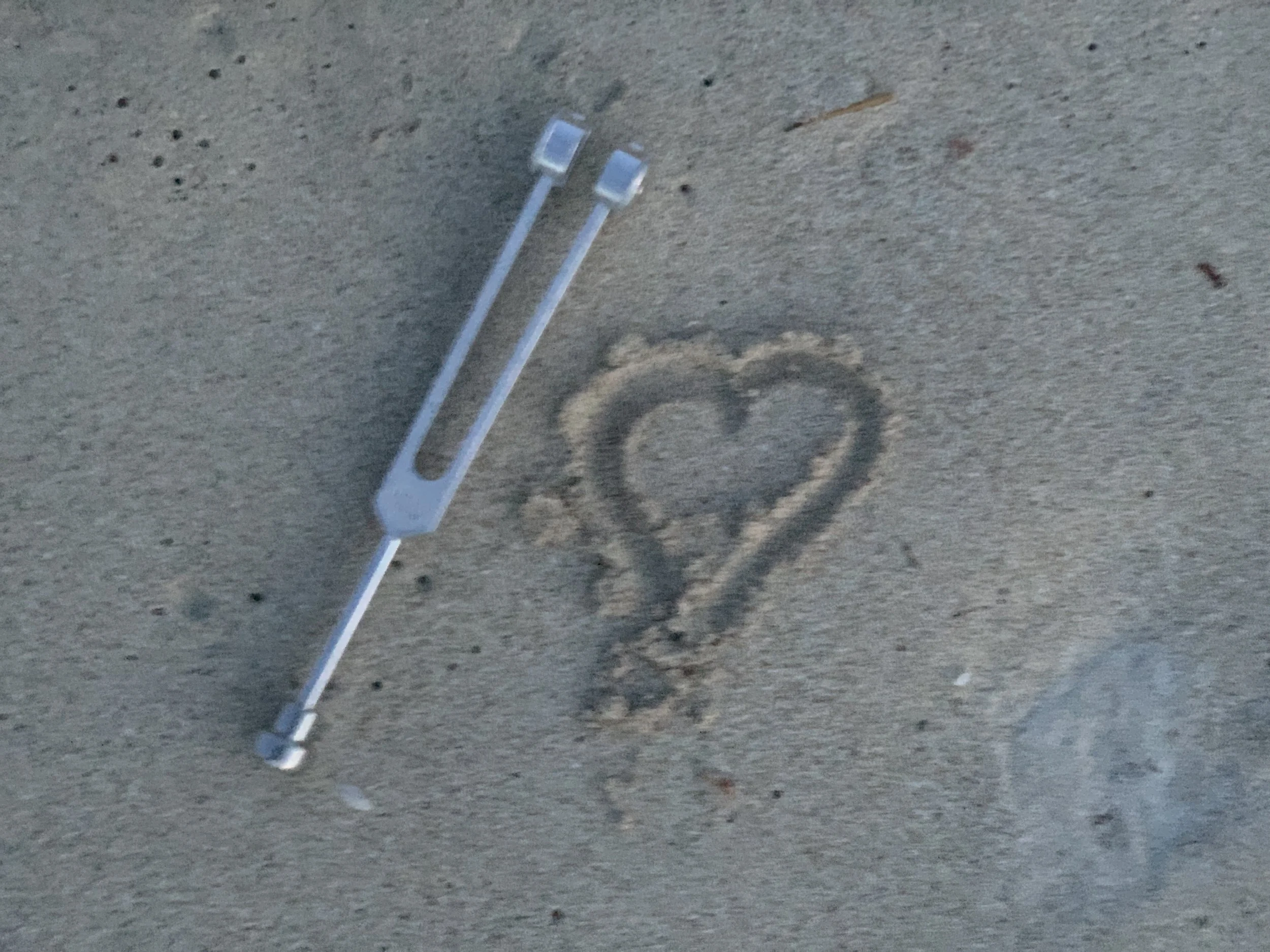 Two long, thin transparent plastic tools with flat, rectangular ends resting on a textured gray surface.