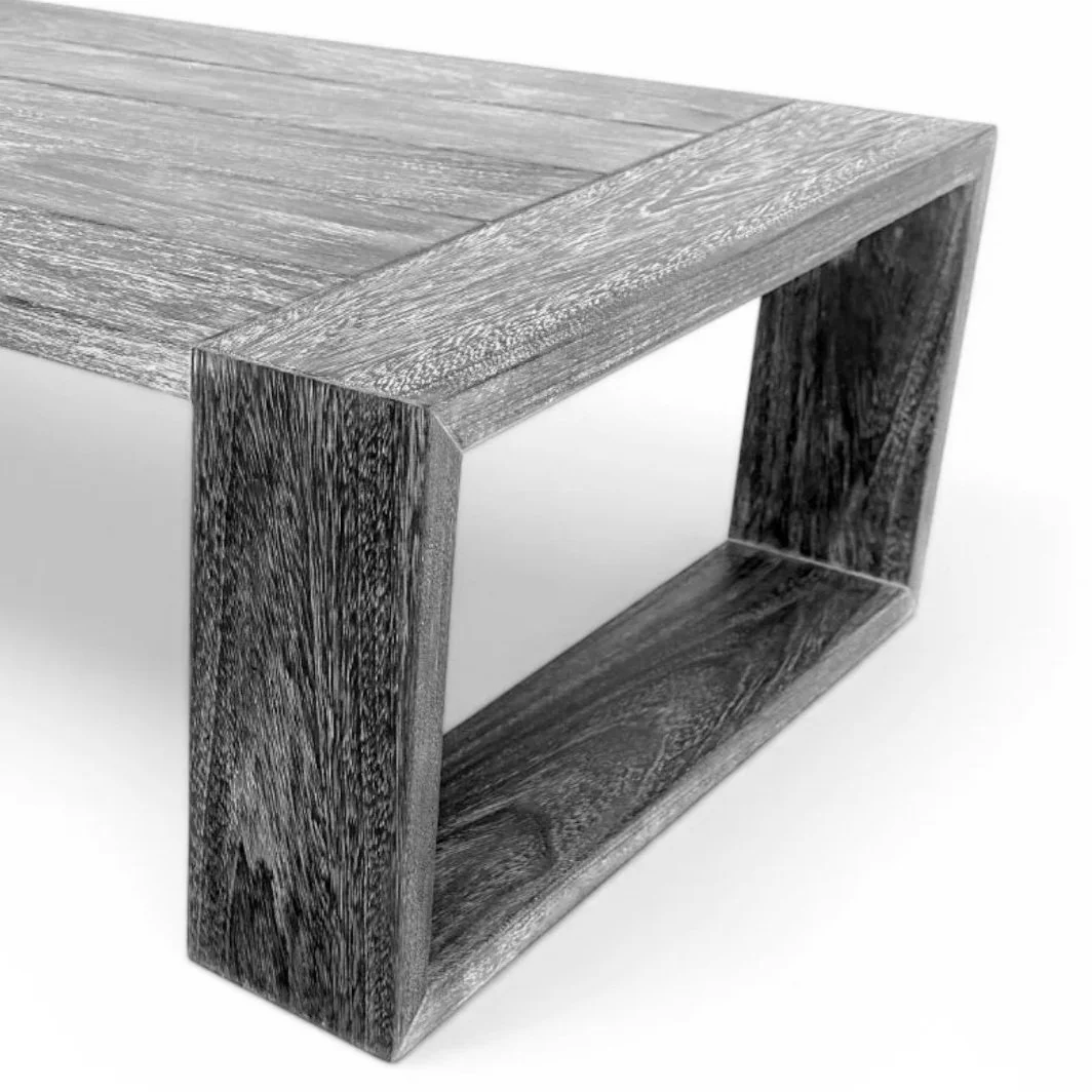 A close-up of a modern wooden table with a rectangular top and an open cuboid base, showcasing a graywashed wood finish.