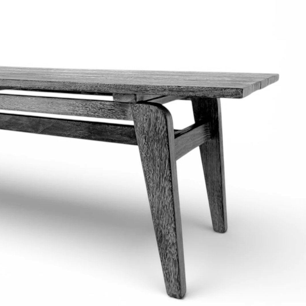 A black and white photo of a wooden table with a modern design, showing a close-up of one corner.
