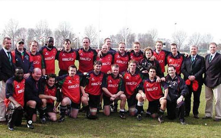 Group photo of a rugby team in red and black uniforms with coaches.