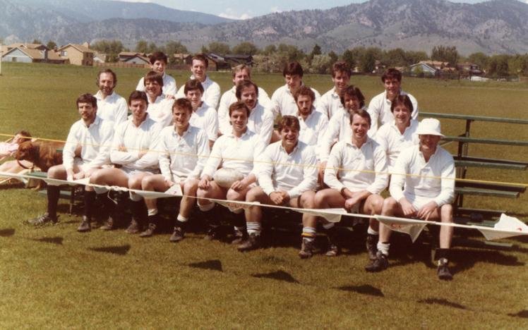 Group of men in cricket uniforms sitting on benches outdoors