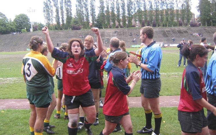 Women rugby players celebrating post-match on a field