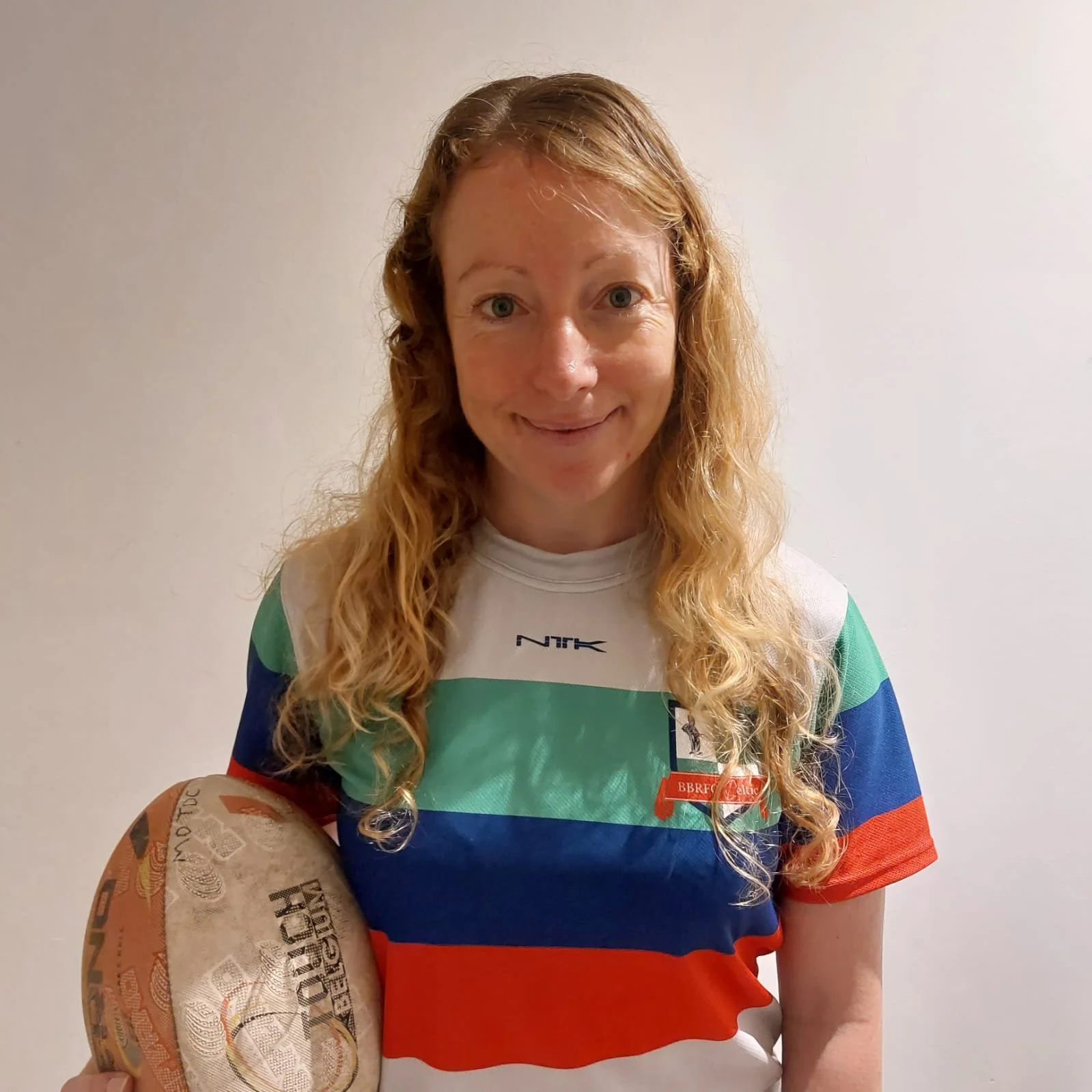 Woman holding rugby ball in colorful striped shirt