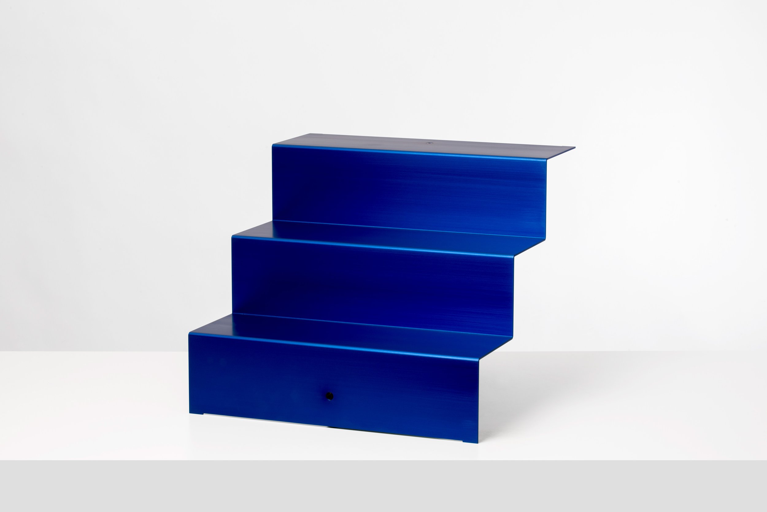 Modern blue tiered step stool with three levels against a white background.